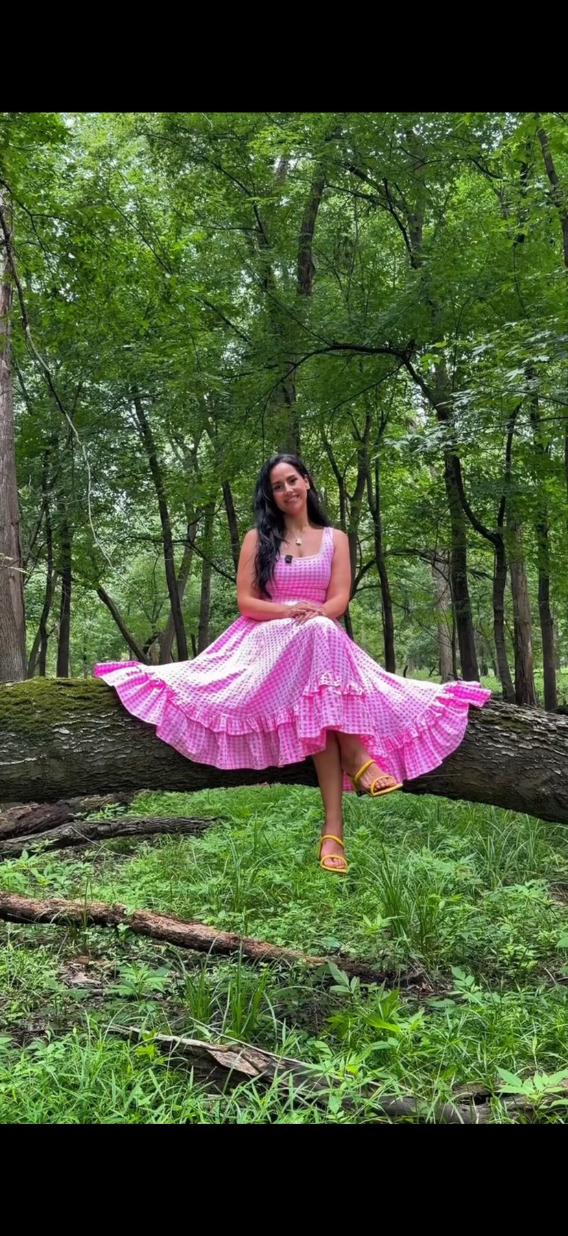 Dra. Amanda Perez sitting on a fallen tree in a pink gingham dress
